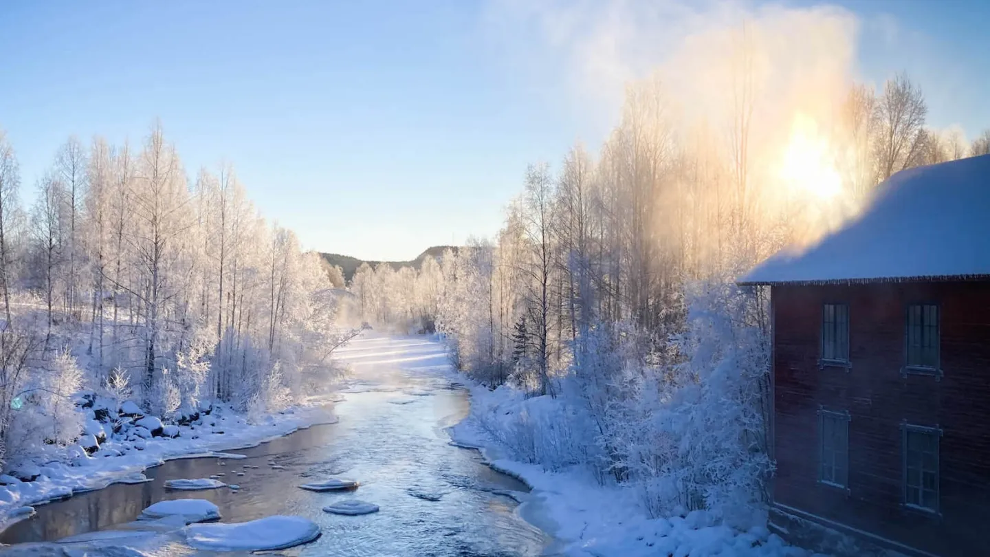 Vinterlandskap, å och träbyggnad i motljus