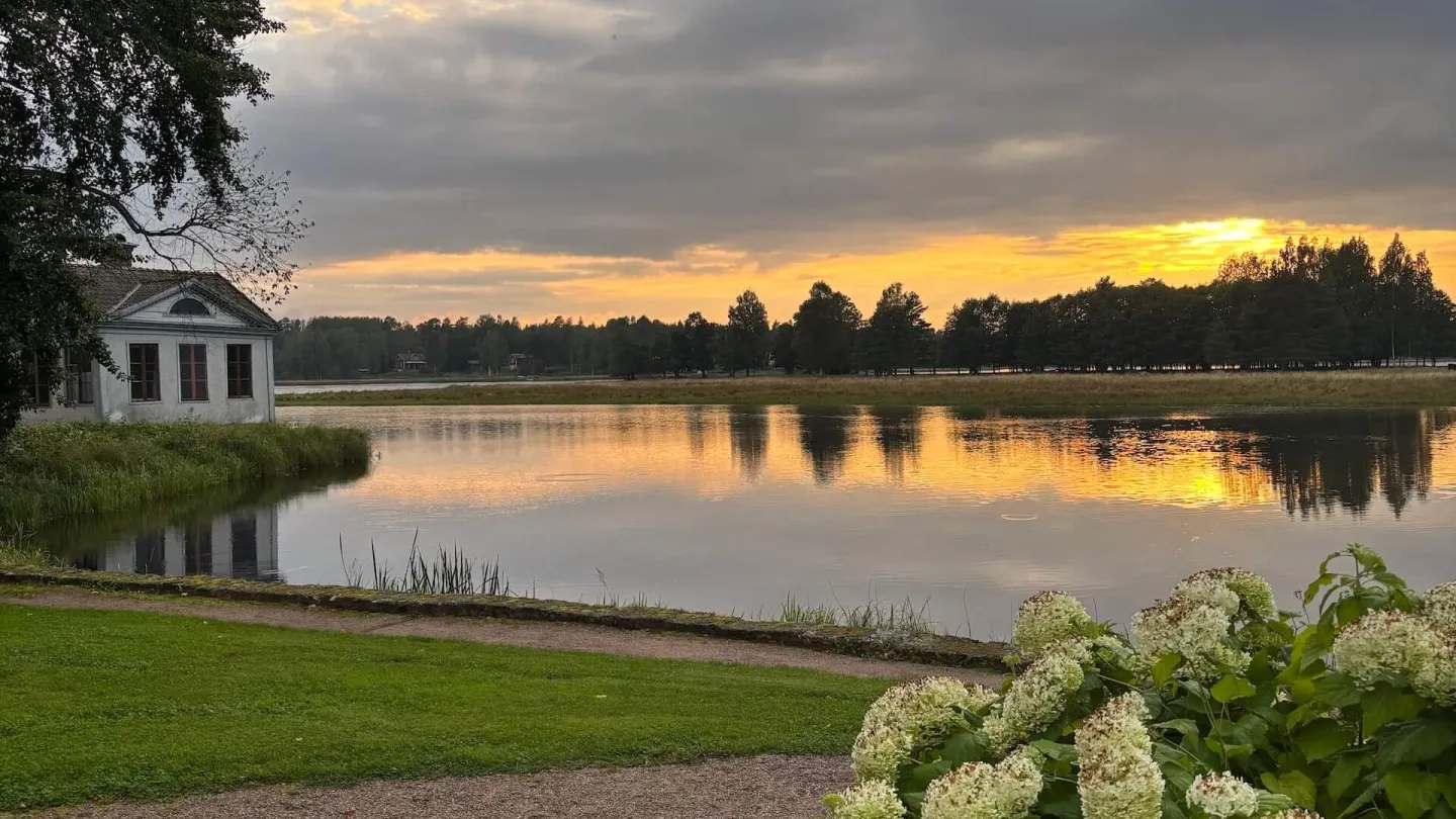 Fin byggnad vid finklippt gräsmatta vid spegelblank sjö