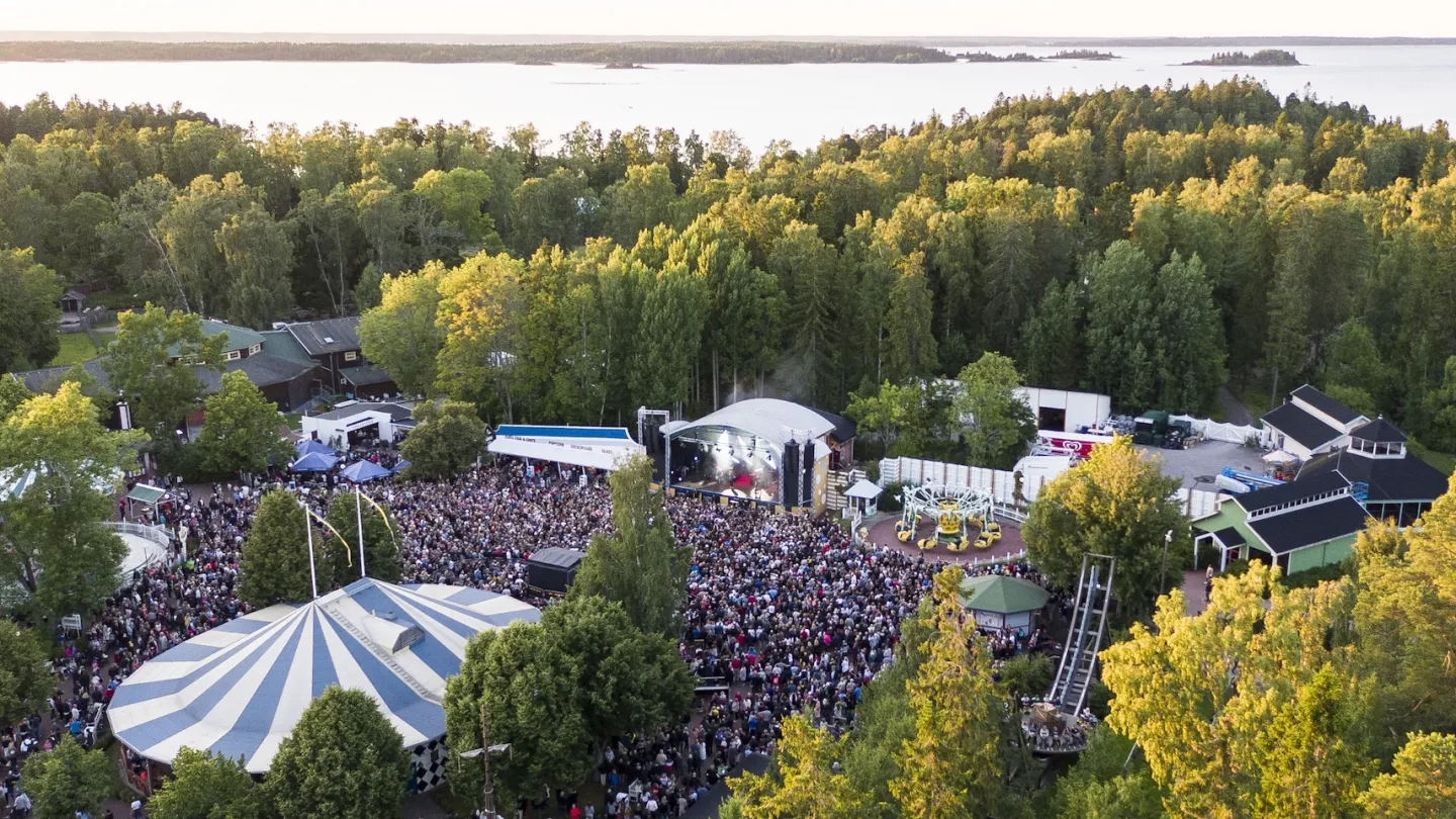 Utomhusscen med stort publikhav och havet i bakgrunden