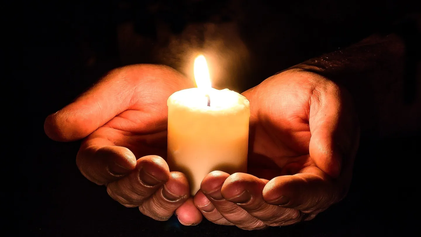 Hands holding a lite candles