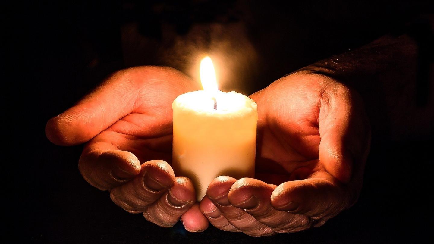 Hands holding a lite candles