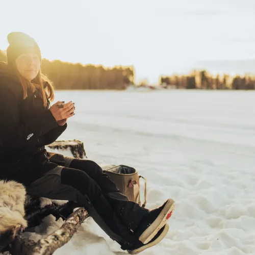 Kvinna sittande på en fäll en fin vinterdag