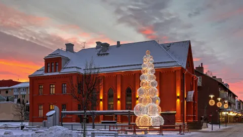 Stor fin röd tegelkyrka med en belyst julgran utanför 