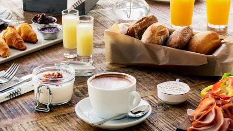 Brunch med kaffe, juice och bröd uppdukat på ett brunt bord