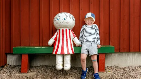 Pojke på bänk med en staty