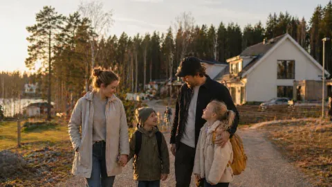 Mamma, pappa med två barn utomhus i villaområde vid vatten