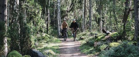 Två cyklister på en grusväg genom skogen
