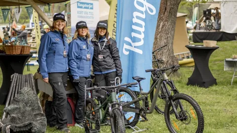 Tre personer står uppradade framfor några cyklar