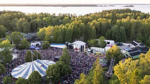 Utomhusscen med stor publik och havet som bakrund