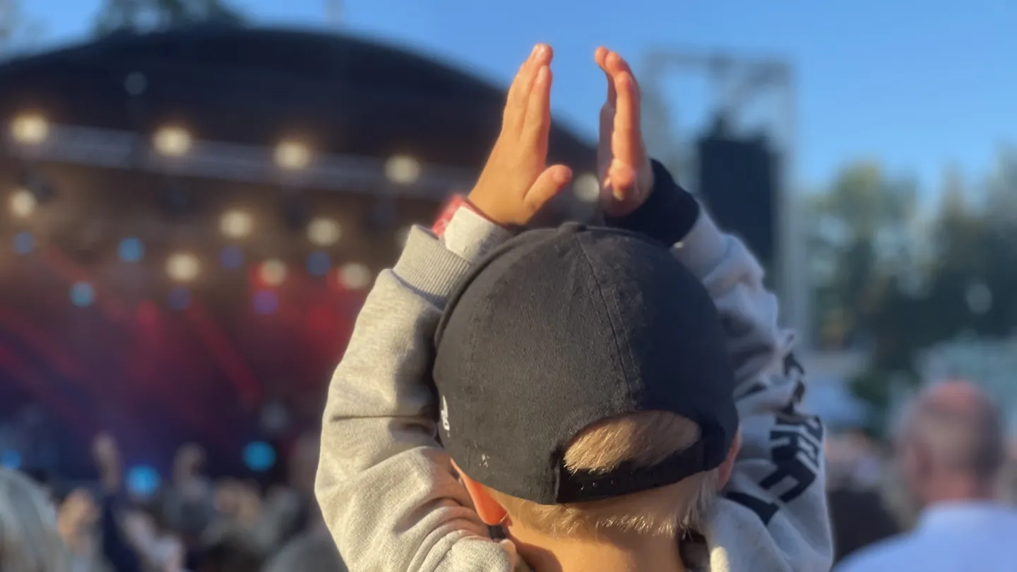 Ung pojke med keps applåderar på en konsert