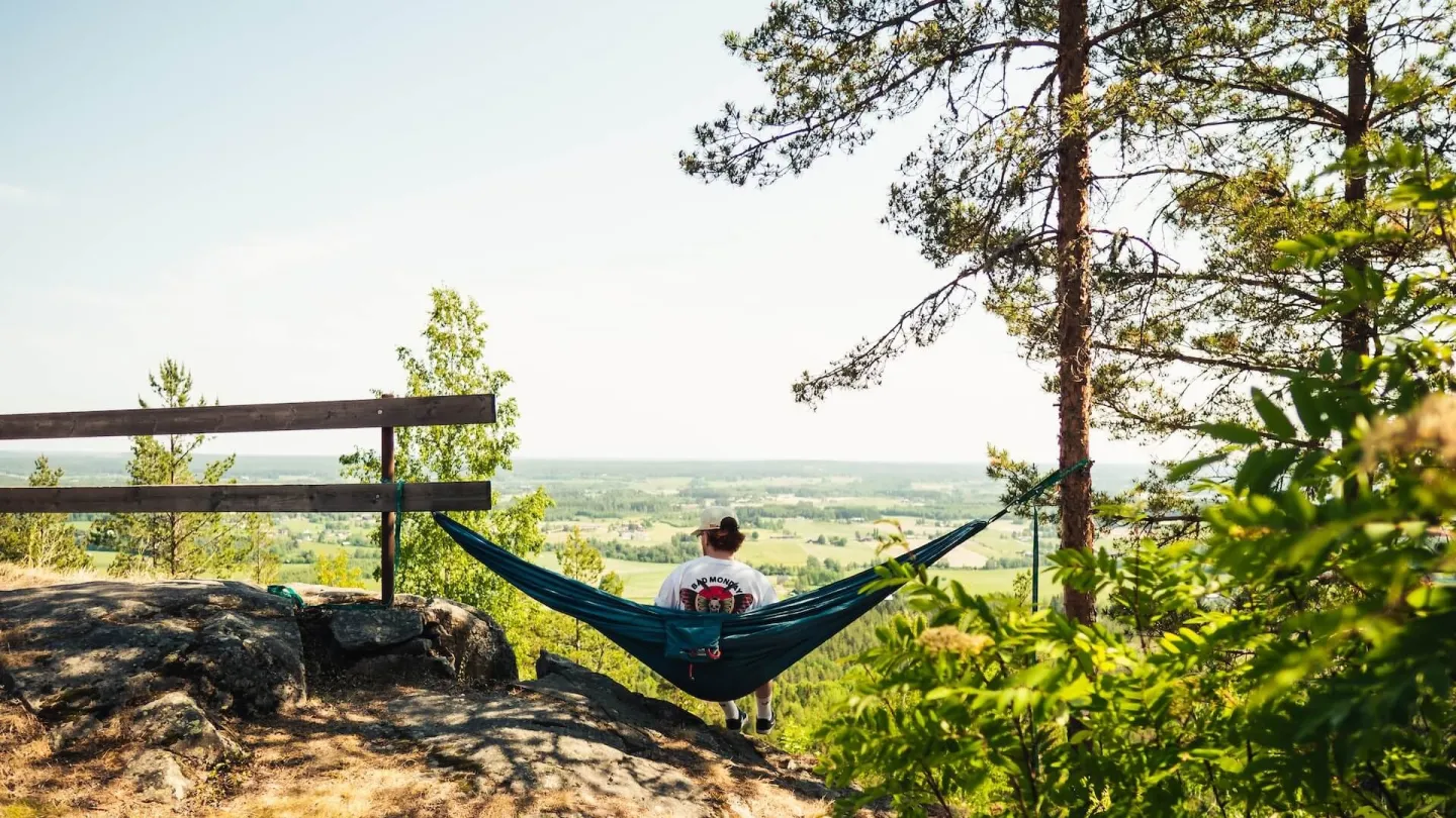 En person sitter i en hängmatta och tittar ut över dalen