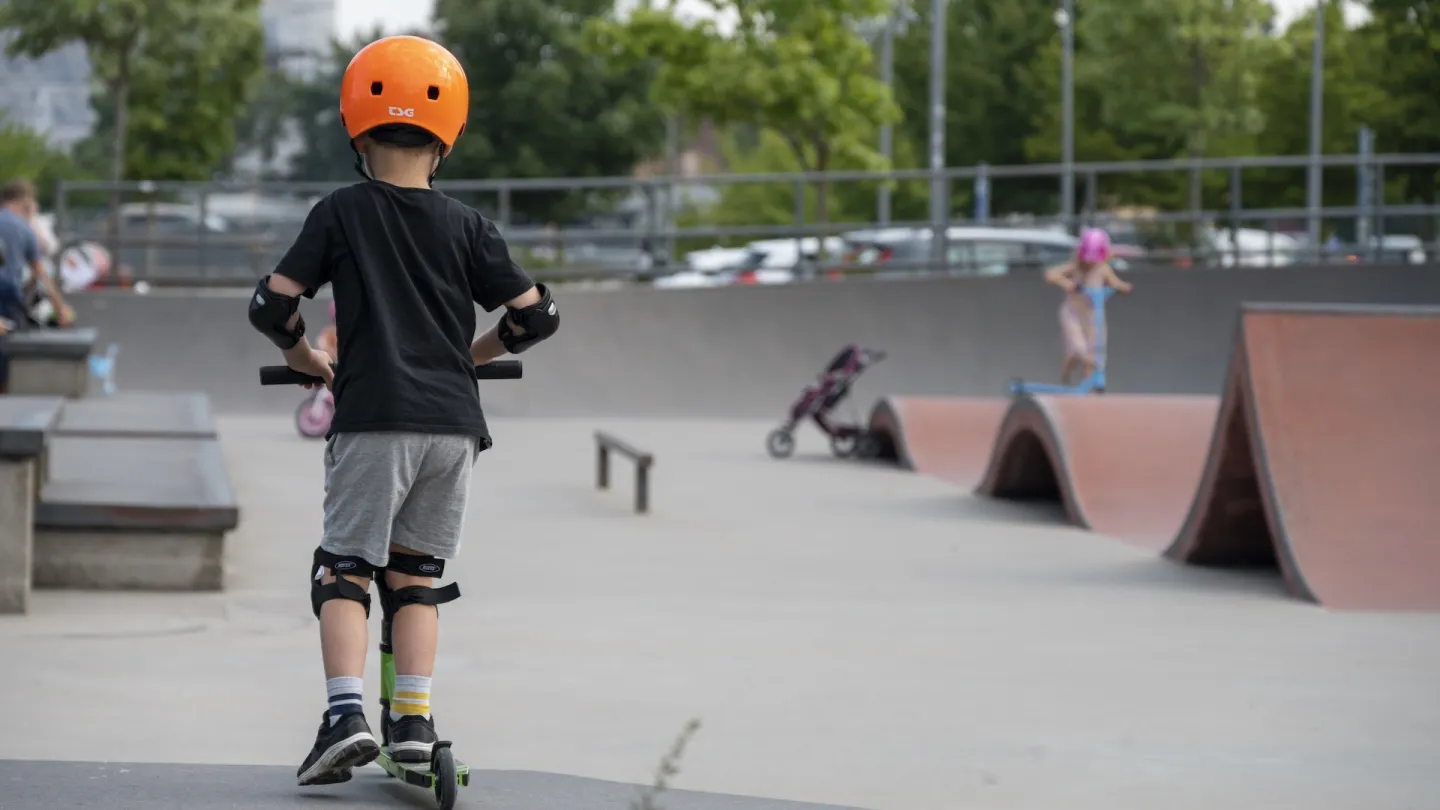 Pojke med hjälp åker bortåt med sparkcykel